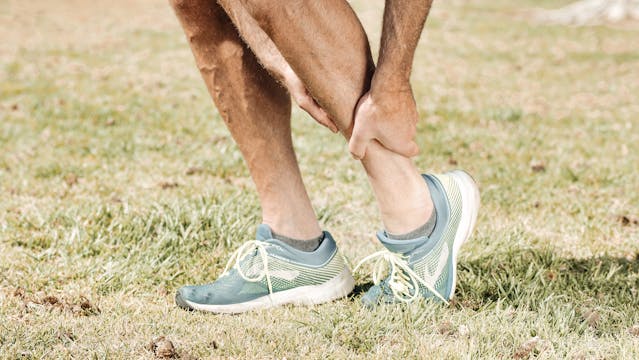 Ankle sprain injury with person holding their ankle, demonstrating common sports-related ankle injury, treated at Ankle and Foot Orthotic Centre, specialists in ankle injury management.